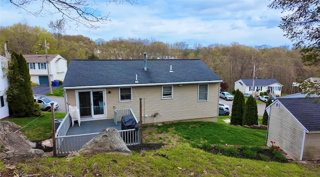 rear view of property featuring a lawn, a patio, a residential view, and roof with shingles