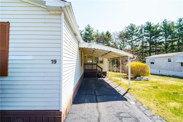 view of side of property featuring a lawn, an attached carport, and aphalt driveway