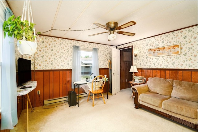 carpeted living room with a wainscoted wall, a baseboard radiator, ornamental molding, and a ceiling fan