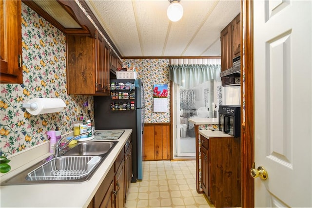 kitchen featuring light floors, a wainscoted wall, wallpapered walls, and brown cabinetry