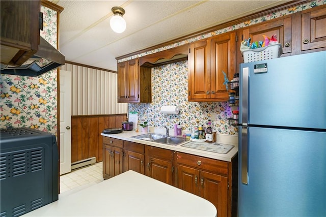 kitchen featuring freestanding refrigerator, wallpapered walls, light countertops, a baseboard heating unit, and a sink