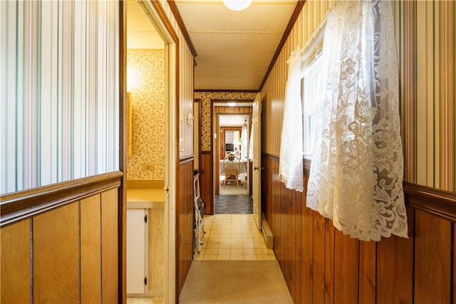 hallway with a wainscoted wall and wallpapered walls