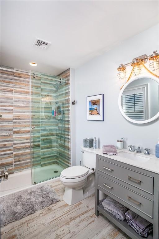 53 Stanton Ave, Narragansett, RI 02882 - bathroom featuring vanity, toilet, a shower stall, wood finished floors, and visible vents