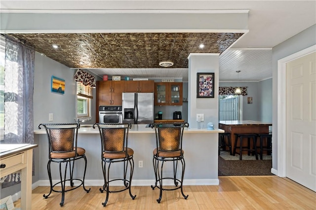 86 Quannacut Rd Unit A, Westerly, RI 02891 - kitchen with stainless steel appliances, an ornate ceiling, light wood-type flooring, a kitchen bar, and a peninsula