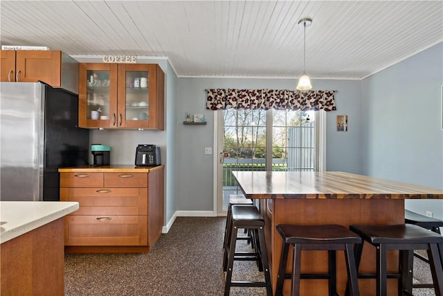 86 Quannacut Rd Unit A, Westerly, RI 02891 - kitchen featuring brown cabinetry, freestanding refrigerator, glass insert cabinets, a breakfast bar area, and hanging light fixtures