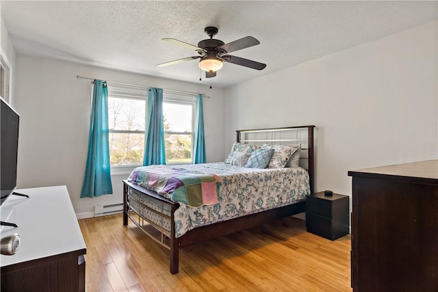 86 Quannacut Rd Unit A, Westerly, RI 02891 - bedroom with a baseboard radiator, light wood-type flooring, ceiling fan, baseboards, and a textured ceiling