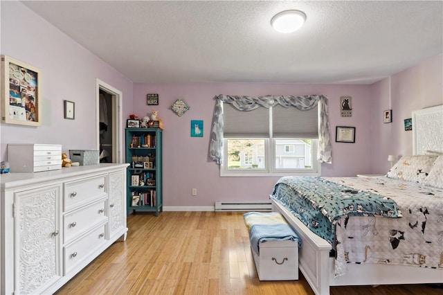 86 Quannacut Rd Unit A, Westerly, RI 02891 - bedroom with baseboard heating, light wood finished floors, baseboards, and a textured ceiling