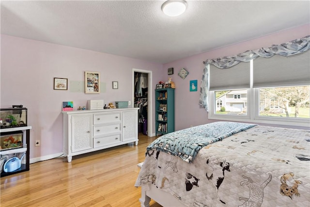 86 Quannacut Rd Unit A, Westerly, RI 02891 - bedroom featuring light wood finished floors, baseboards, a spacious closet, and a textured ceiling