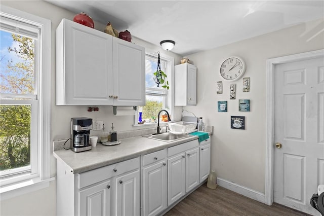 kitchen featuring a sink, light countertops, baseboards, dark wood-style floors, and white cabinetry