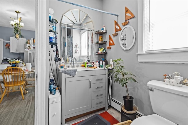 bathroom featuring vanity, a baseboard radiator, wood finished floors, and toilet