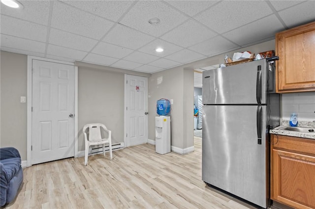 kitchen featuring light wood-type flooring, freestanding refrigerator, a paneled ceiling, and brown cabinets