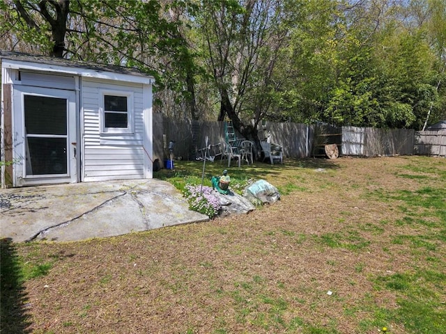 view of yard featuring a fenced backyard, an outbuilding, and a patio area