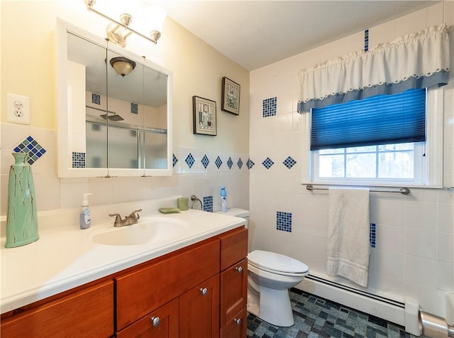 bathroom with vanity, toilet, tile walls, a baseboard heating unit, and a shower with shower door