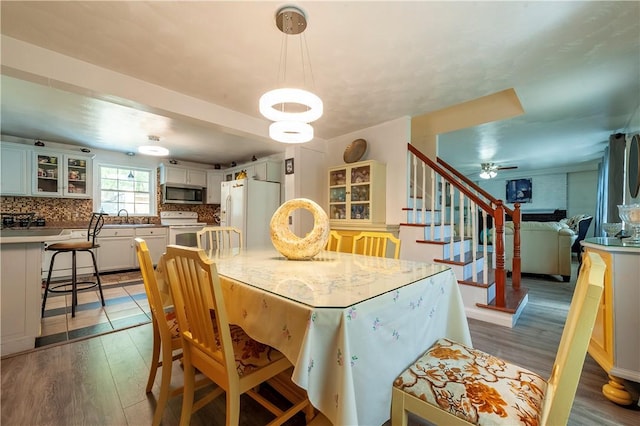 dining space with a ceiling fan, stairs, and wood finished floors