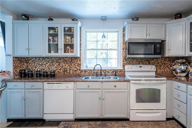 kitchen featuring a sink, decorative backsplash, white appliances, and glass insert cabinets