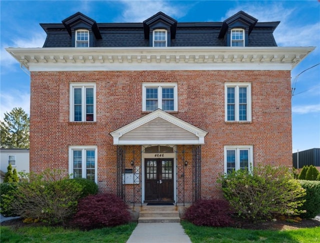victorian home with brick siding, mansard roof, and french doors