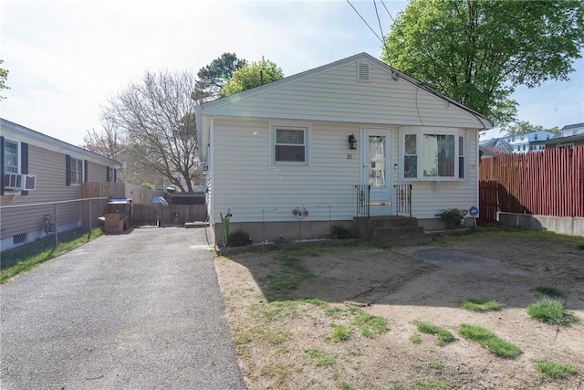 bungalow-style house featuring fence, cooling unit, and driveway