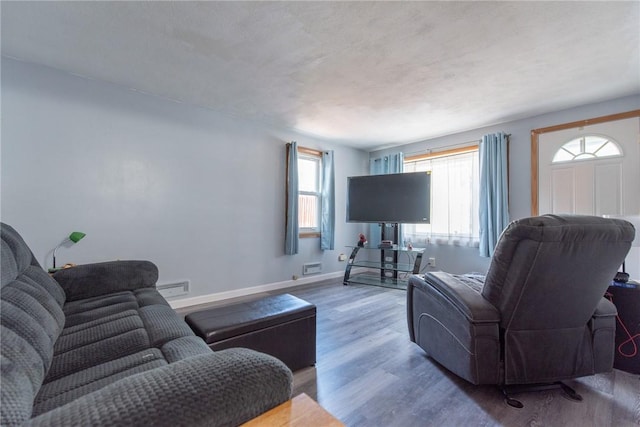 living area featuring baseboards, a baseboard radiator, wood finished floors, and visible vents