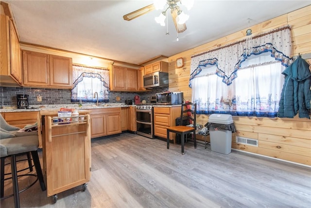 kitchen featuring visible vents, decorative backsplash, light wood-type flooring, a ceiling fan, and appliances with stainless steel finishes