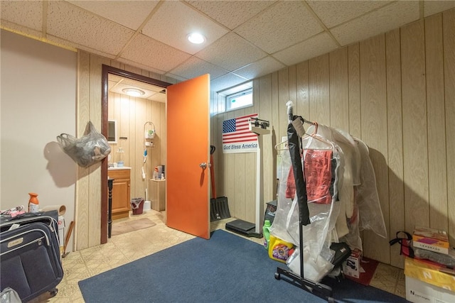 exercise area featuring a paneled ceiling and wooden walls