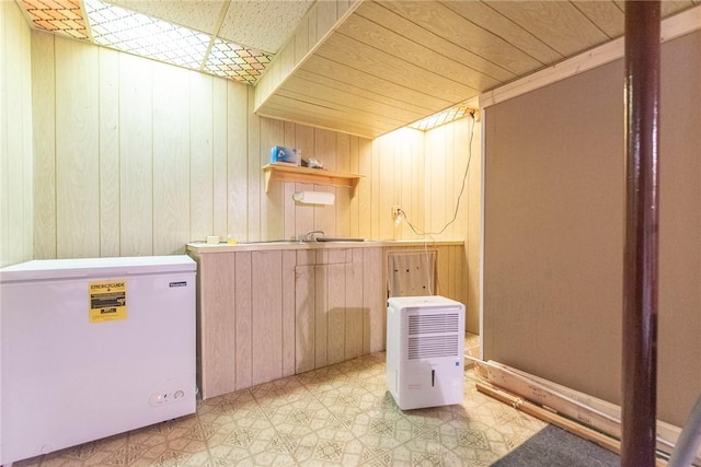 laundry area with light floors and wood walls