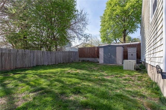 view of yard featuring central air condition unit, an outbuilding, a fenced backyard, and a storage unit