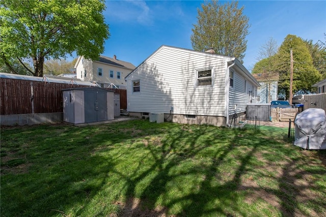 rear view of house with a fenced backyard, a yard, and a storage shed