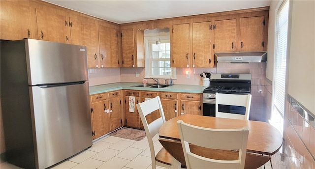 kitchen featuring appliances with stainless steel finishes, tasteful backsplash, brown cabinets, a sink, and extractor fan