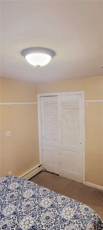 bedroom with carpet floors, baseboard heating, and a closet