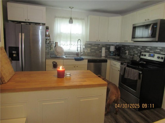 kitchen with backsplash, appliances with stainless steel finishes, a sink, white cabinets, and wood counters