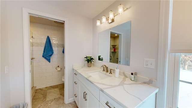 bathroom with vanity, a tile shower, and toilet