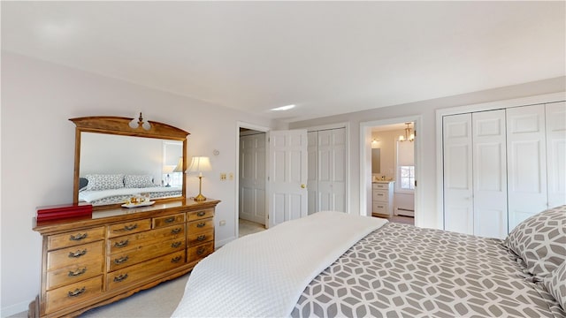 bedroom featuring ensuite bathroom, baseboard heating, and two closets
