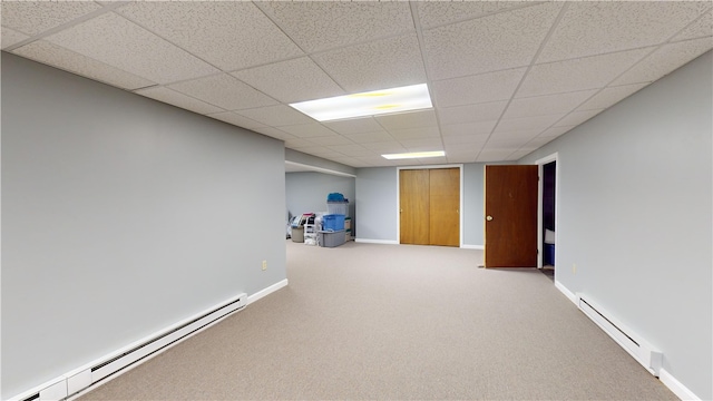 finished basement featuring a paneled ceiling, baseboard heating, baseboards, a baseboard radiator, and carpet flooring