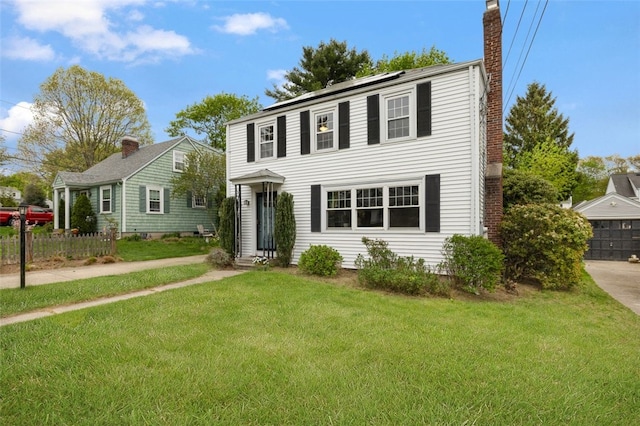 view of front of house featuring a chimney, solar panels, and a front lawn
