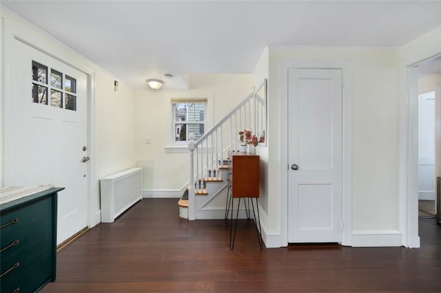 entryway featuring crown molding, radiator heating unit, stairs, baseboards, and wood finished floors