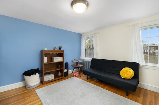 sitting room featuring radiator heating unit, baseboards, and wood finished floors