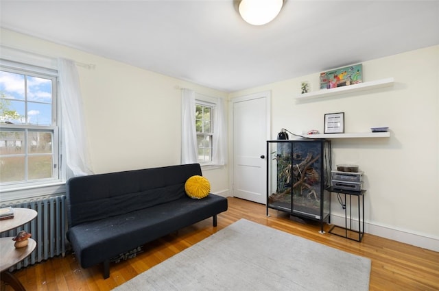 living area featuring a healthy amount of sunlight, radiator, baseboards, and wood finished floors