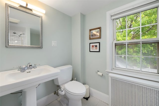 bathroom featuring toilet, baseboards, radiator heating unit, tile patterned floors, and a sink