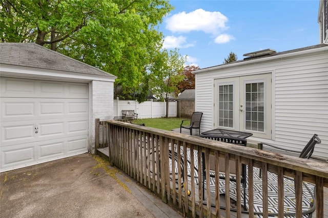 wooden deck with concrete driveway, fence, french doors, and an outdoor structure