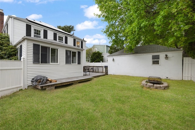 back of house featuring fence private yard, an outdoor fire pit, and a yard