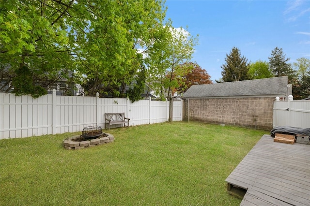 view of yard with a fenced backyard, a fire pit, and a deck