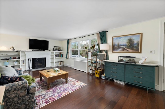 living area with a fireplace with flush hearth, radiator, and dark wood-style flooring