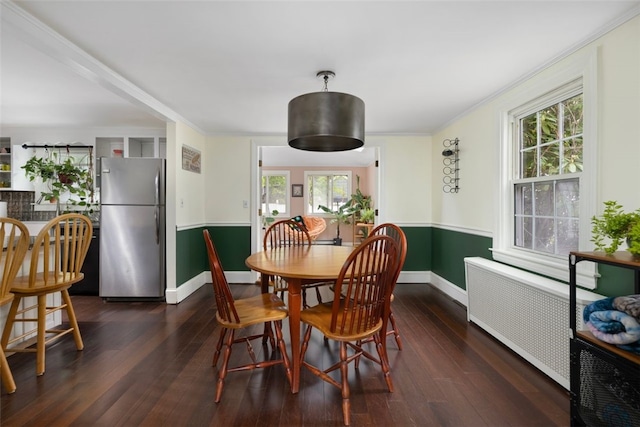 dining room featuring radiator heating unit, baseboards, ornamental molding, and dark wood-style flooring