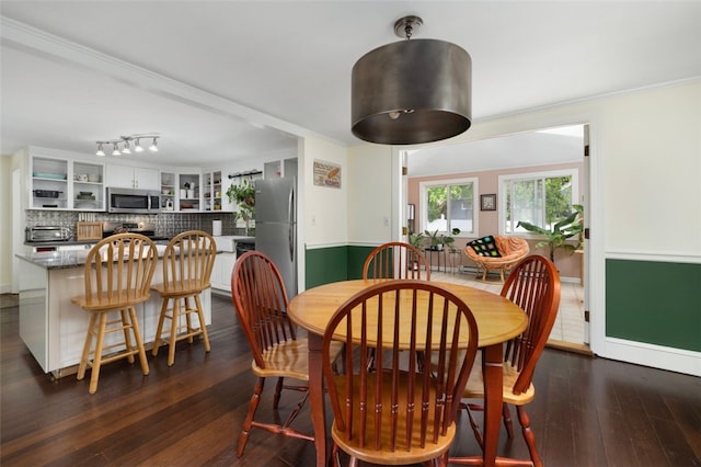 dining space with crown molding and dark wood-style flooring