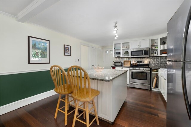 kitchen featuring dark wood-style flooring, open shelves, appliances with stainless steel finishes, backsplash, and a kitchen island