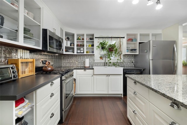 kitchen with stainless steel appliances, open shelves, a sink, and tasteful backsplash