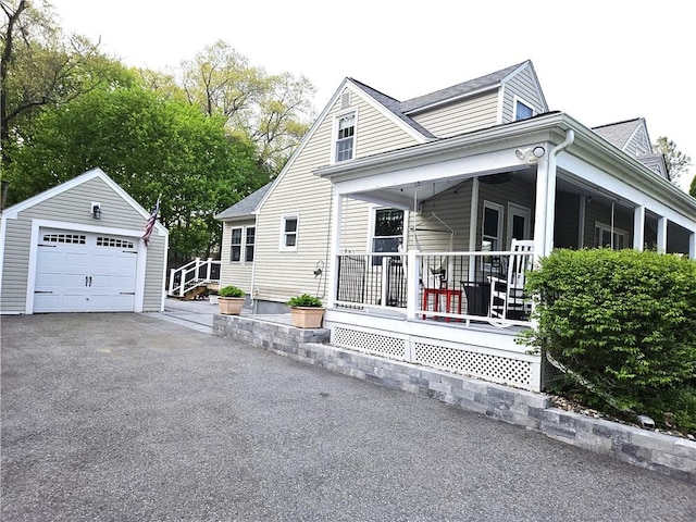 view of front of house with a garage, an outdoor structure, a porch, and aphalt driveway
