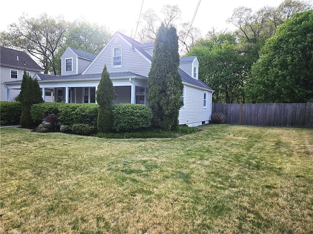 view of home's exterior with fence, a shingled roof, and a lawn
