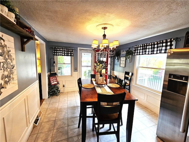 dining space featuring an inviting chandelier, a wainscoted wall, and a decorative wall