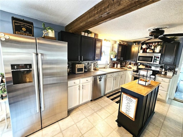 kitchen with a textured ceiling, a sink, wood counters, stainless steel appliances, and white cabinetry